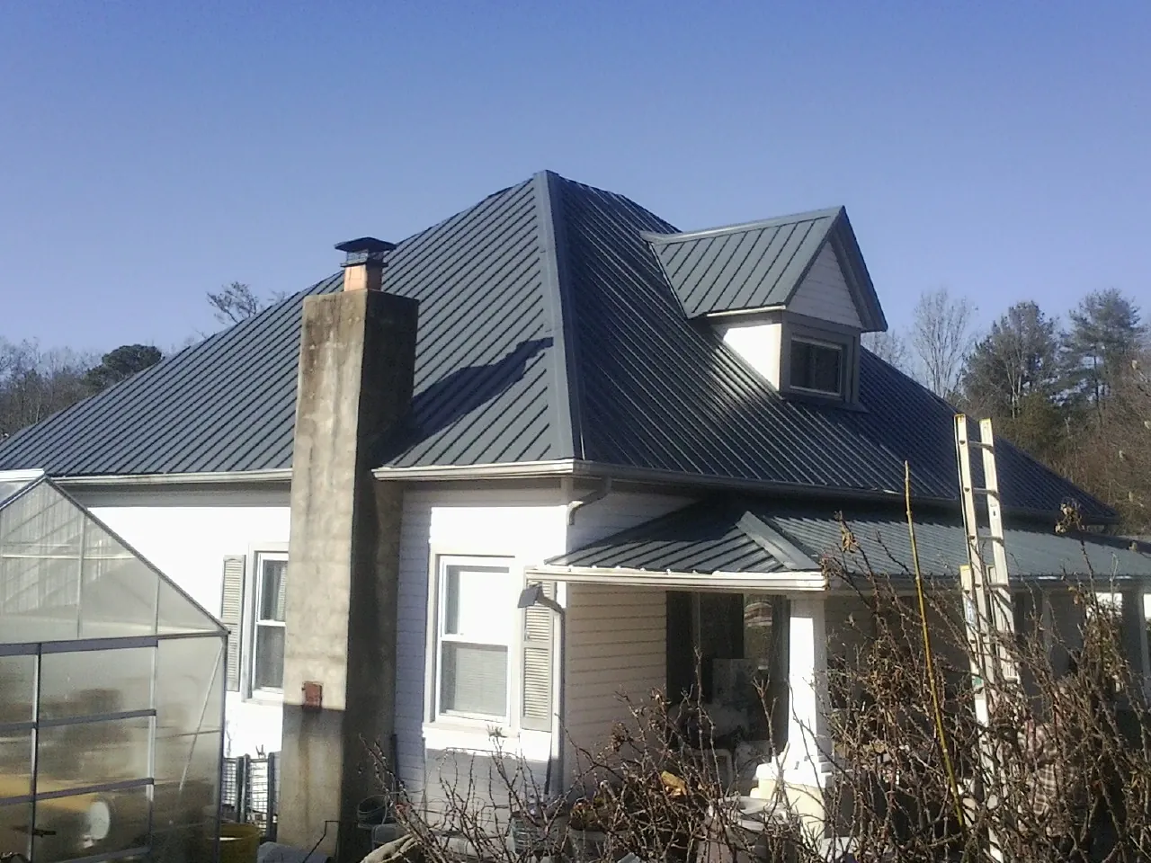 Dark blue standing seam metal roof on a white farmhouse with dormer — Slate & Tile Roof Repair by Roofing Brothers in Toughkenamon