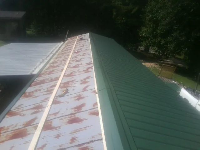 Old rusted panels beside newly installed green metal roofing — Wind Damage Roof Repair by Roofing Brothers in Toughkenamon