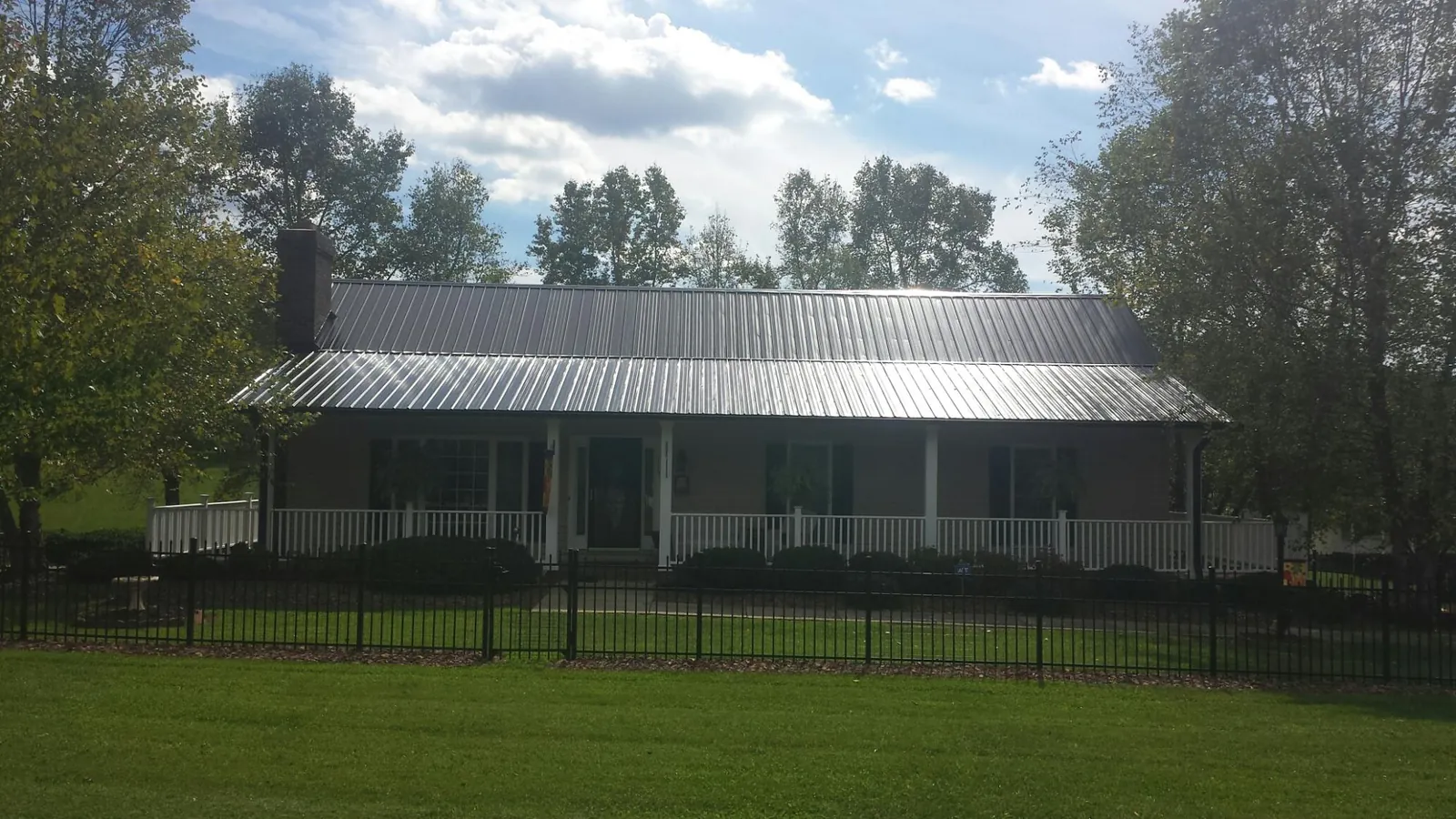 Gray metal roof on a brick ranch with a full width front porch — Gutter Guard Installation work by our crew in Toughkenamon