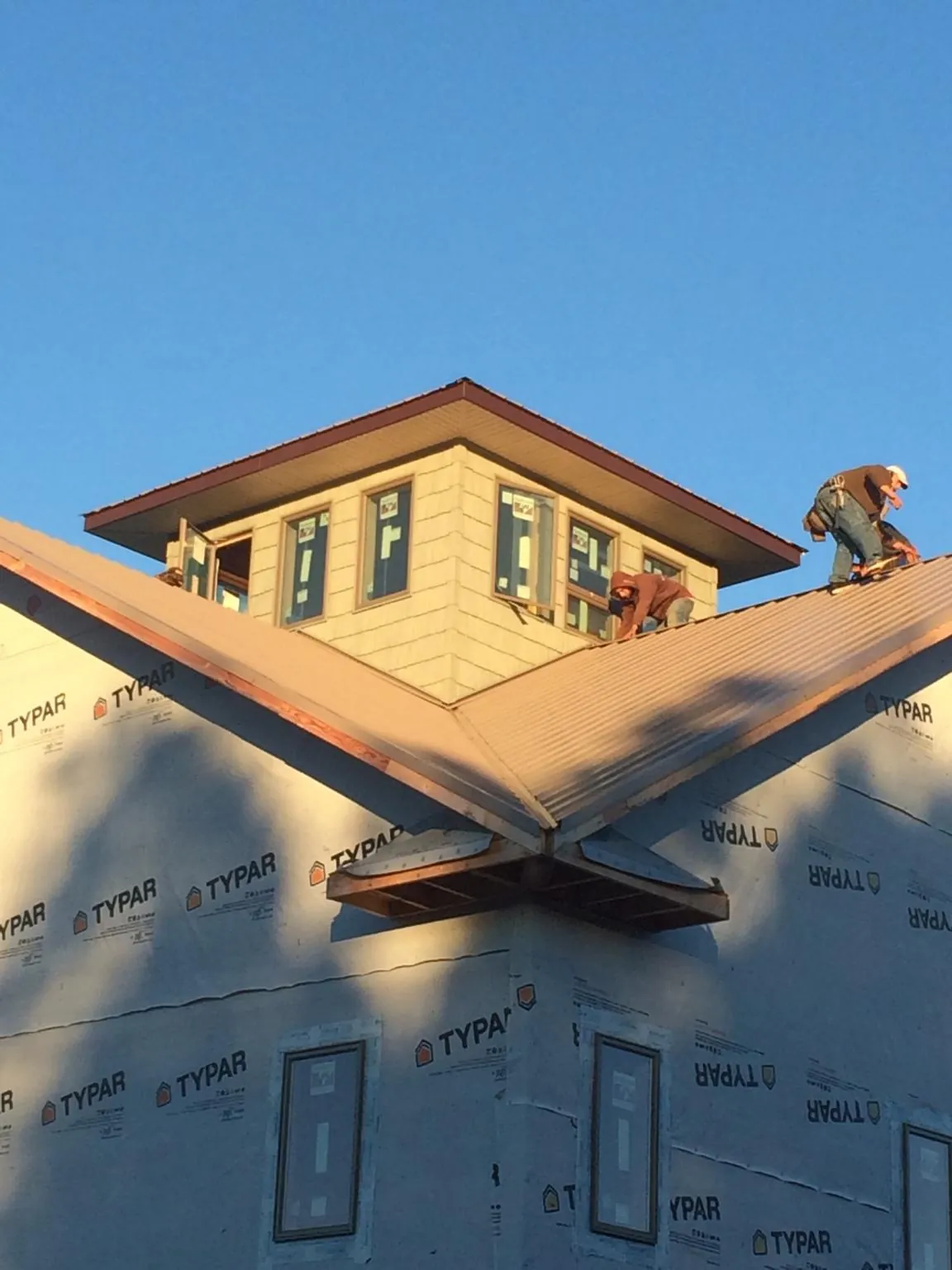 Roofers working around a rooftop cupola on a new metal roof at sunset — Roof Waterproofing in Toughkenamon by Roofing Brothers